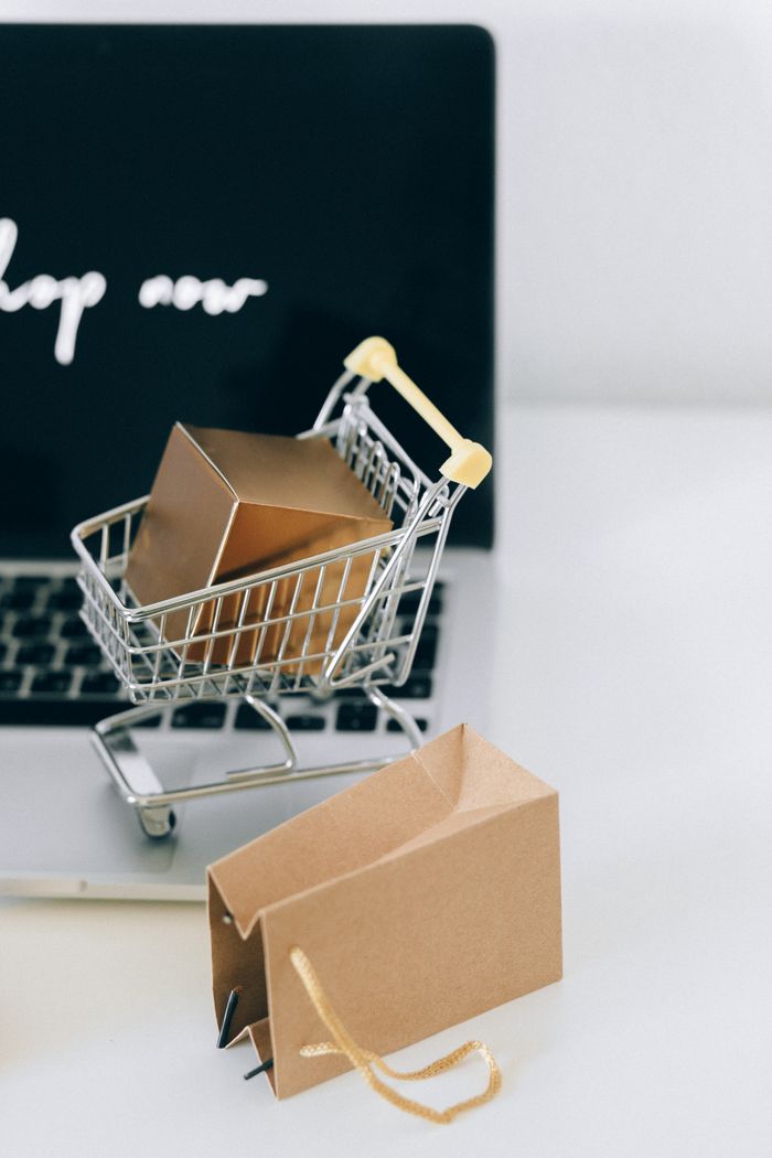 project-01-c A miniature shopping cart with a parcel on a laptop symbolizes online shopping and e-commerce.